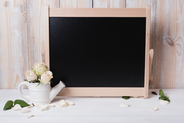 Blank blackboard with beautiful roses on wooden table