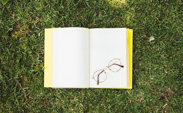 Free photo blank book with glasses on meadow