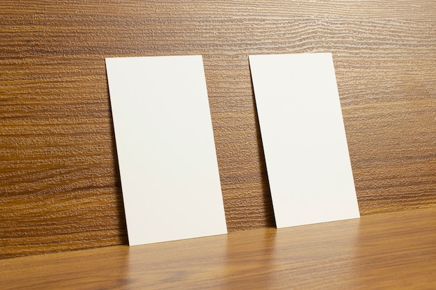 Пустые визитки на деревянном текстурированном столе размером 3,5 х 2 дюйма