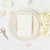 無料写真 バラとセラミックプレート上の空のカード;はさみ、結婚指輪、白背景