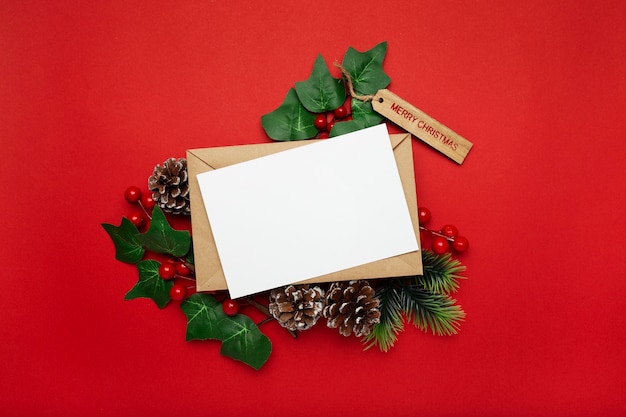 Free photo blank card with mistletoe and pine cones on red table