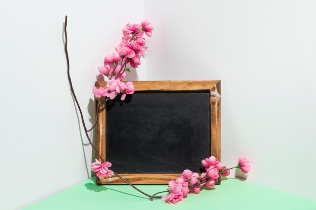 Blank chalkboard with flowers branch on table