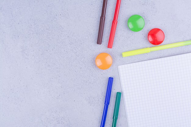 A blank checked paper with multicolor pins and pencils around