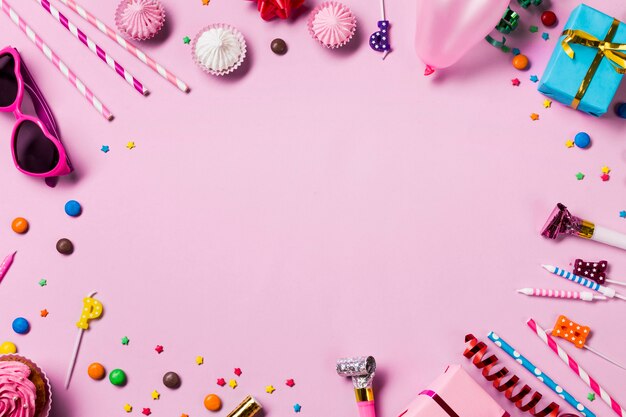 ピンクの背景の誕生日パーティーアイテムで作られた空白の円形フレーム