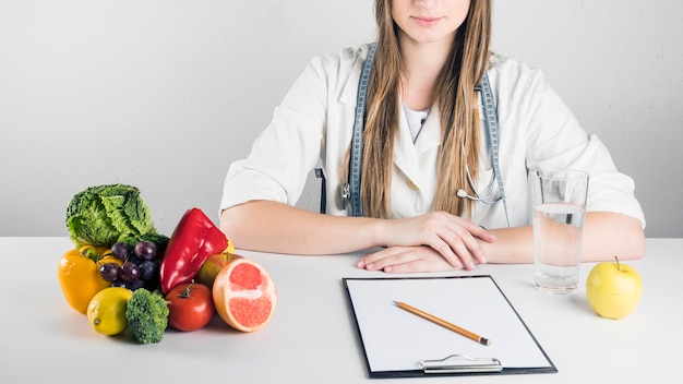 Appunti bianco; cibo sano e bicchiere d'acqua sulla scrivania