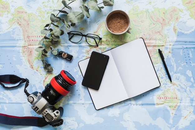 Free photo blank diary, personal accessories, and coffee cup on the world map