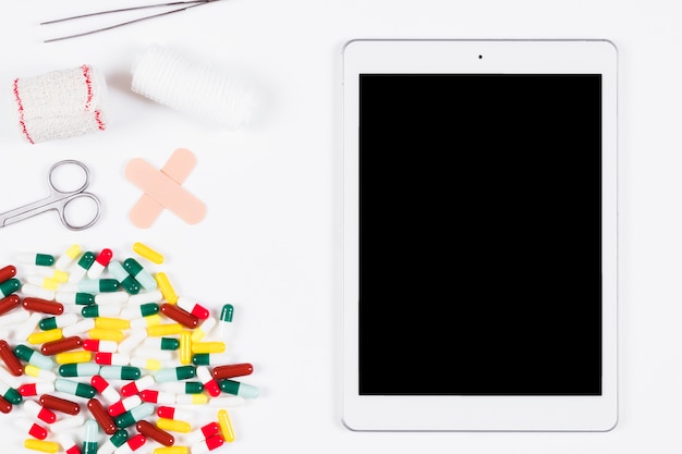 Blank digital tablet with medical supplies and equipments on white background