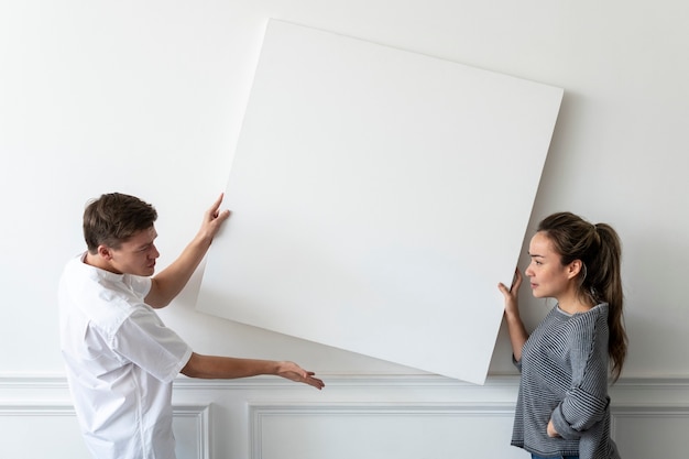 Free photo blank frame being hung by a couple