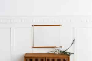 Free photo blank frame hanging above a wooden cabinet