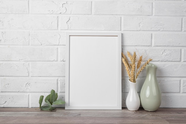 Free photo blank frame on shelf beside vase