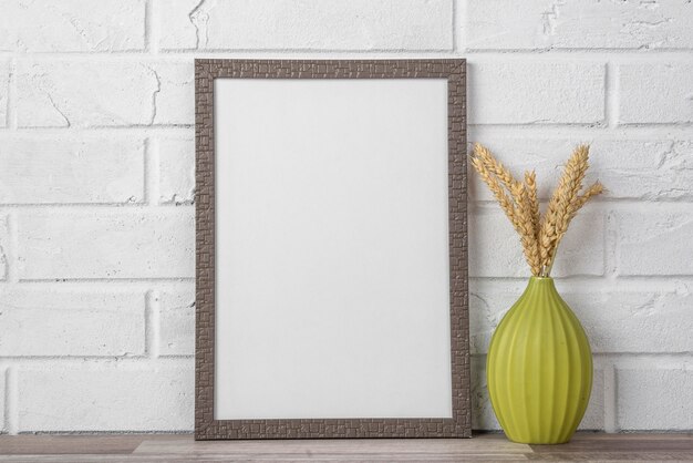 Blank frame on shelf beside vase