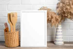 Free photo blank frame next to vase and kitchen ustensils