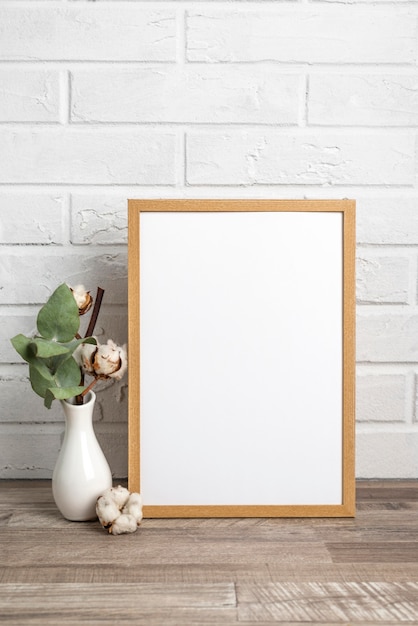 Free photo blank frame next to vase with cotton