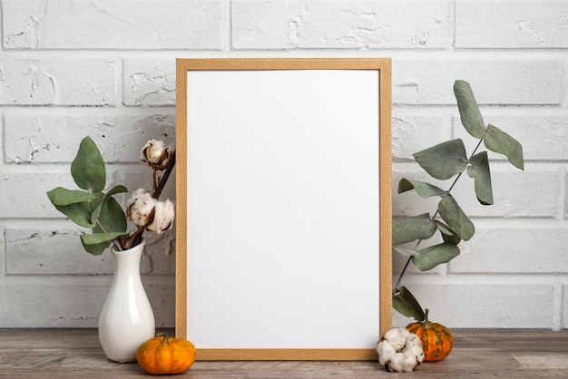 Free photo blank frame next to vase with cotton