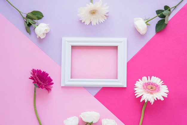 Blank frame with different flowers on table