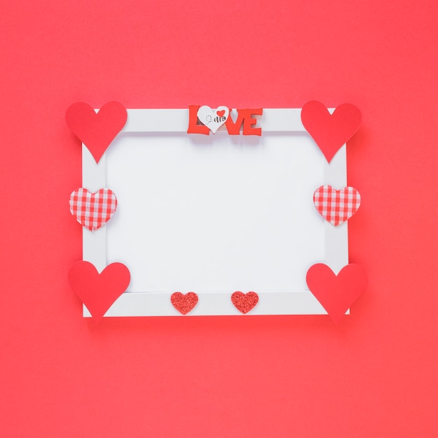 Free photo blank frame with different hearts on table