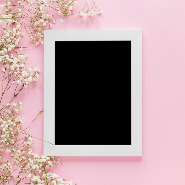 Blank frame with flowers branches on table