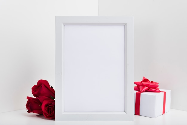 Free photo blank frame with gift box and red roses