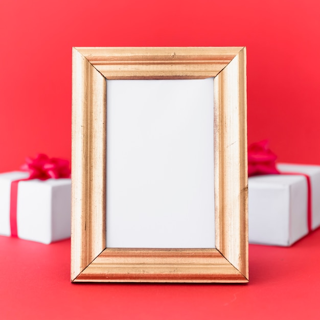 Blank frame with gift boxes on table