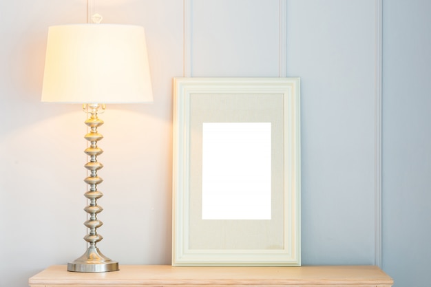 Blank frame with light lamp decoration on table