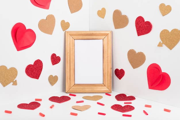 Blank frame with paper hearts on table