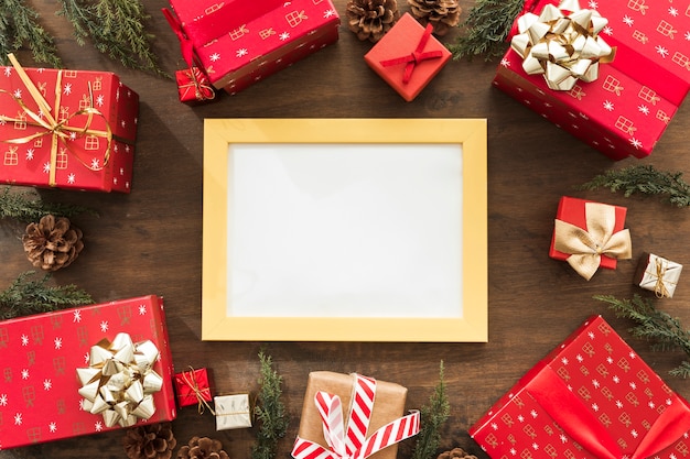 Blank frame with red gift boxes on table 