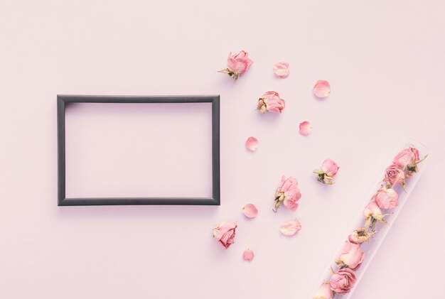 Blank frame with rose petals on table