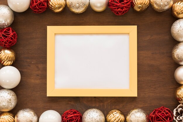 Blank frame with shiny baubles on table 