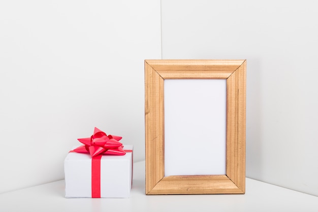 Blank frame with small gift box on table