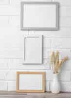 Free photo blank frames on wall next to vase