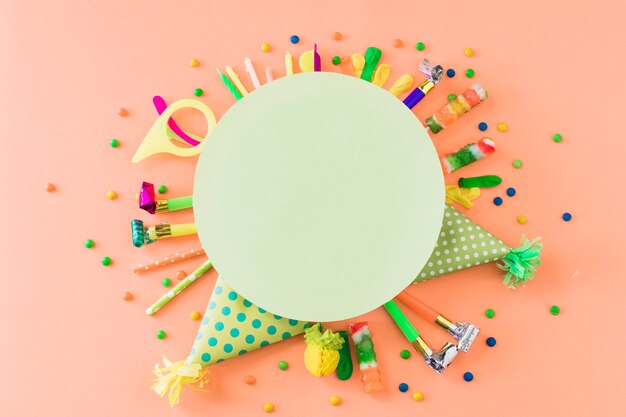 Blank green frame over party accessories and candies on orange backdrop