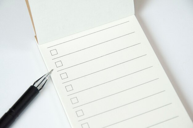 Бланк для планирования списка с контрольным списком и черной ручкой на белом фоне, крупным планом
