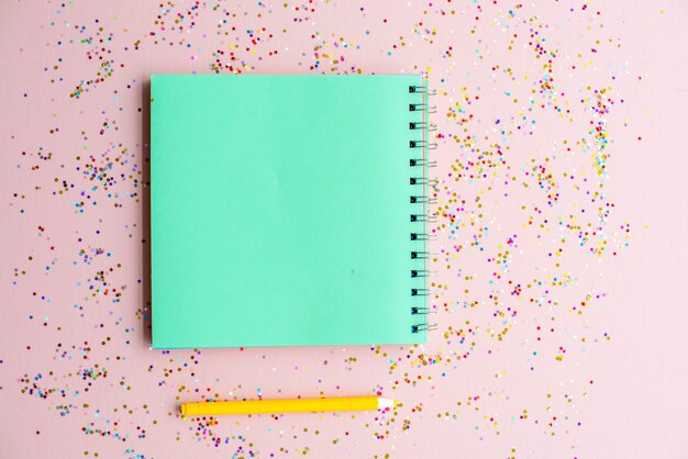 Blank notebook and pen with confetti