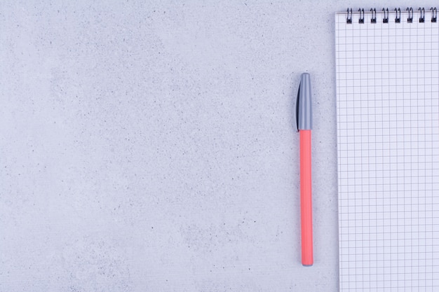 A blank notebook with color pencils around on grey surface