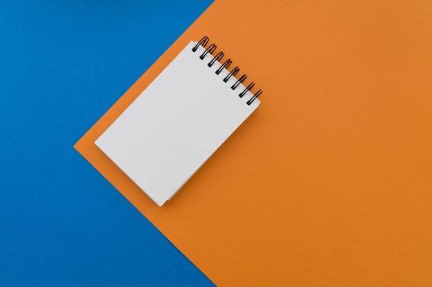 Blank notepad on blue and orange background
