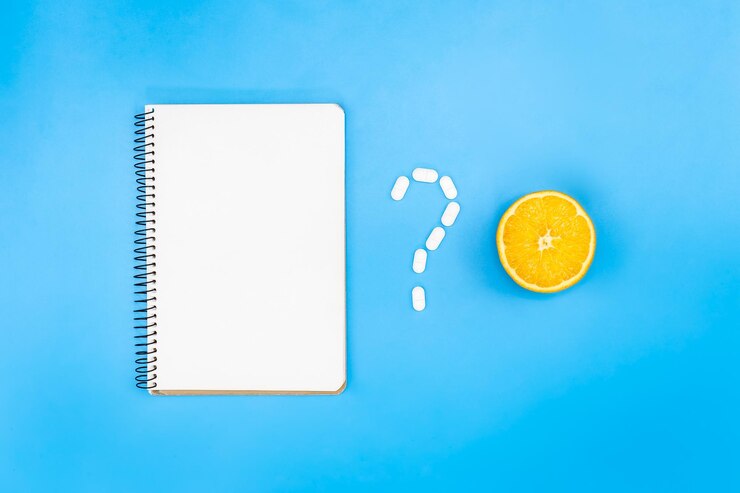 मुफ़्त फोटो blank notepad and orange on blue background flat lay