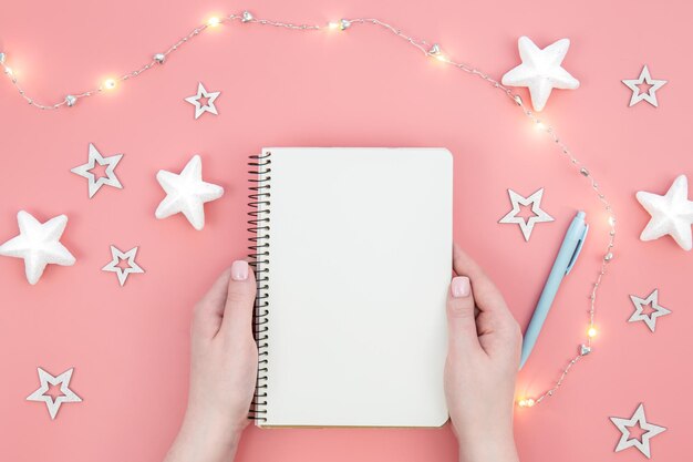 Blank notepad on pink background and decorative stars and garland flat lay