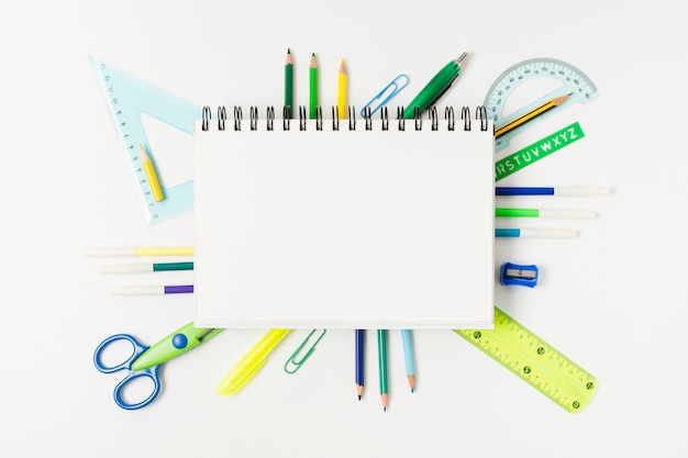 Blank notepad surrounded by desk supplies