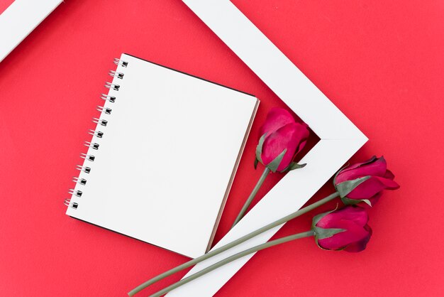 Blank notepad with red roses in frame