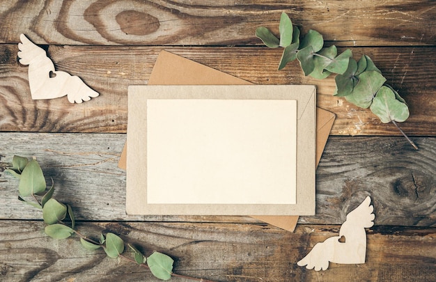 無料写真 ユーカリの小枝フラット レイアウトと木製の背景に空白の紙と封筒
