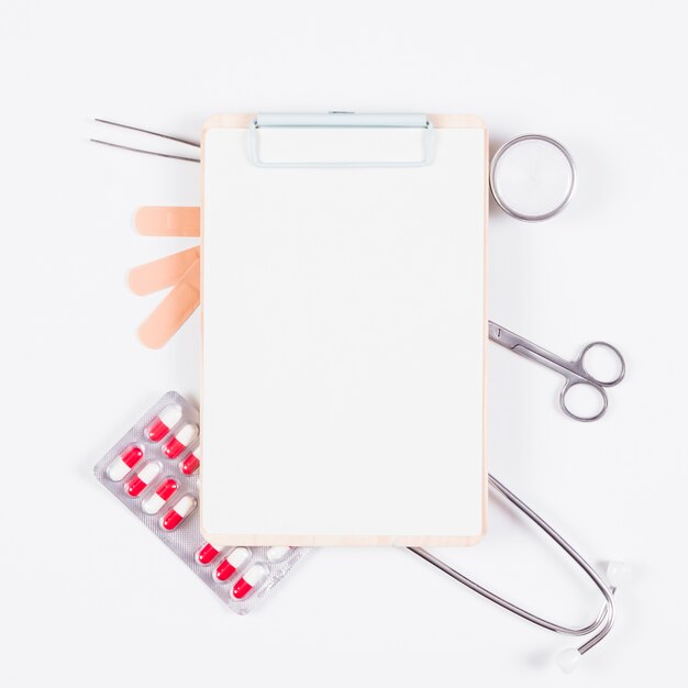 Blank paper on clipboard over the medical equipments on white background