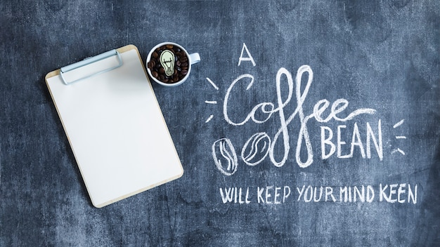 Blank paper on clipboard with coffee beans mug and text on blackboard