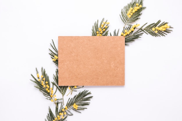 Blank paper on green plant branches on table