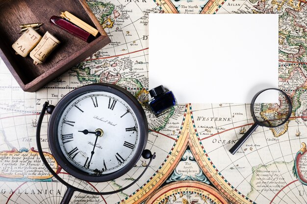 Blank paper, magnifying glass and ink bottle on historic map