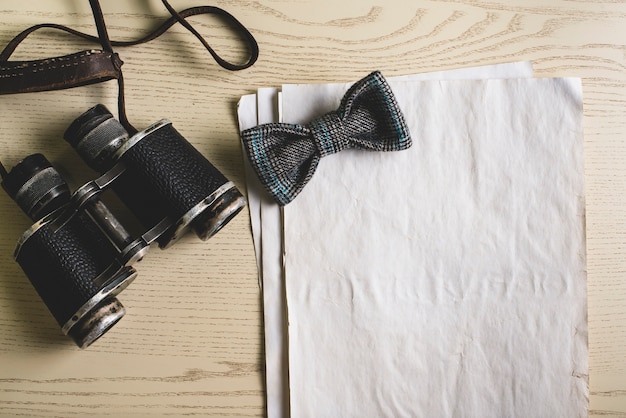 Blank paper with bow tie and binoculars