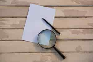 Free photo blank paper with a magnifying glass and a pencil