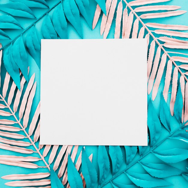 Blank paper with pink and blue palm leaves on blue background