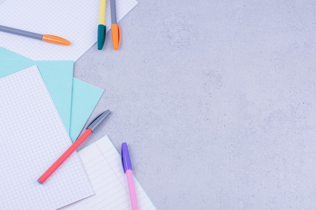 Чистые бумаги и разноцветные ручки, изолированные на серой поверхности