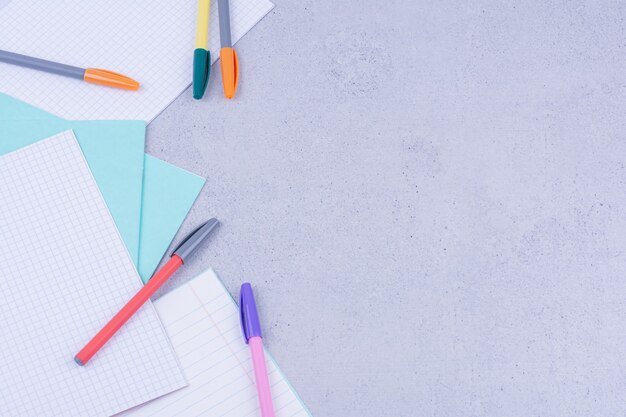 Blank papers and multicolor pens isolated on grey surface