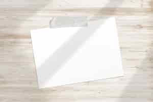 Free photo blank photo frame glued with adhesive tape to wooden textured with soft window shadows adobe